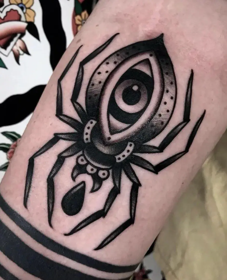 A black spider tattoo with an eye on it.