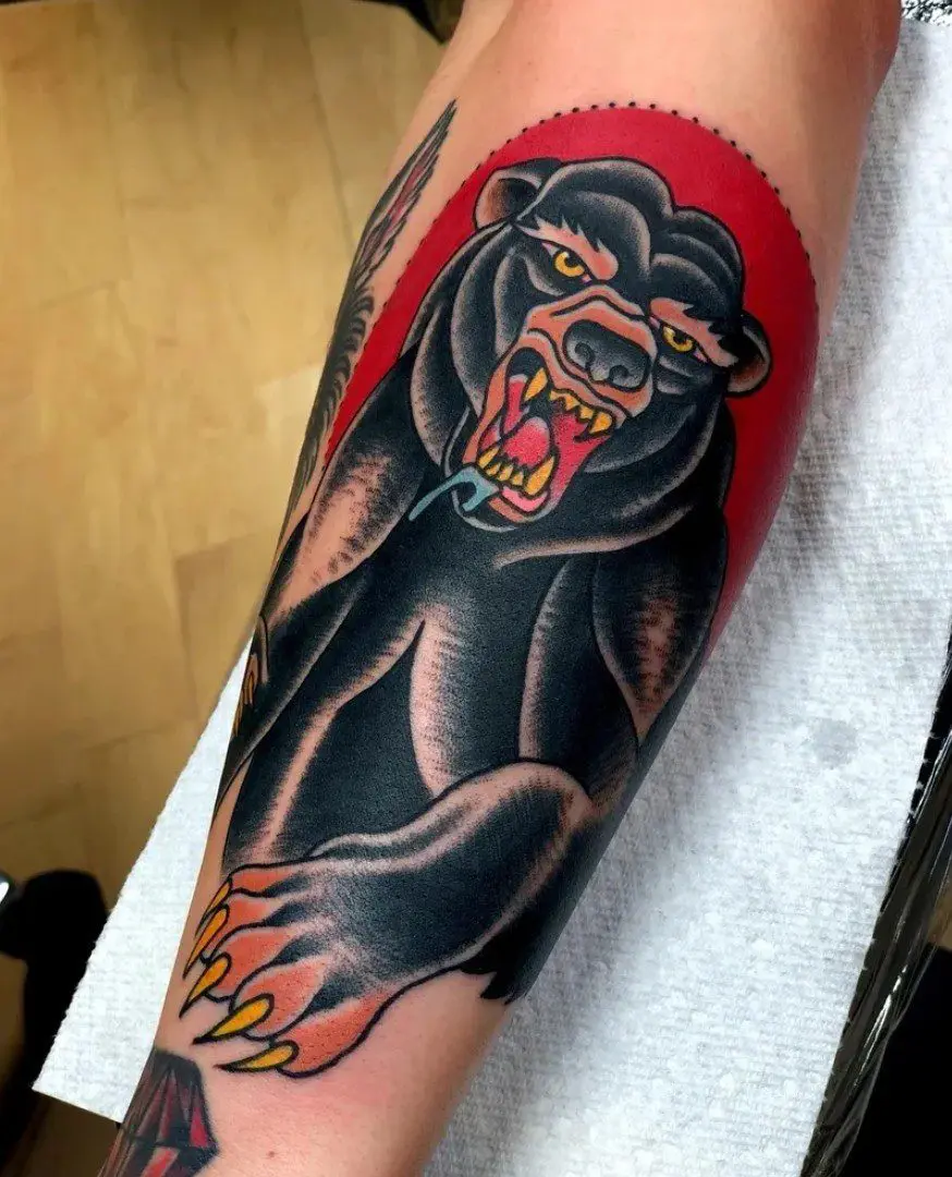 A tattoo of a bear with its mouth open rendered in the American Traditional style
