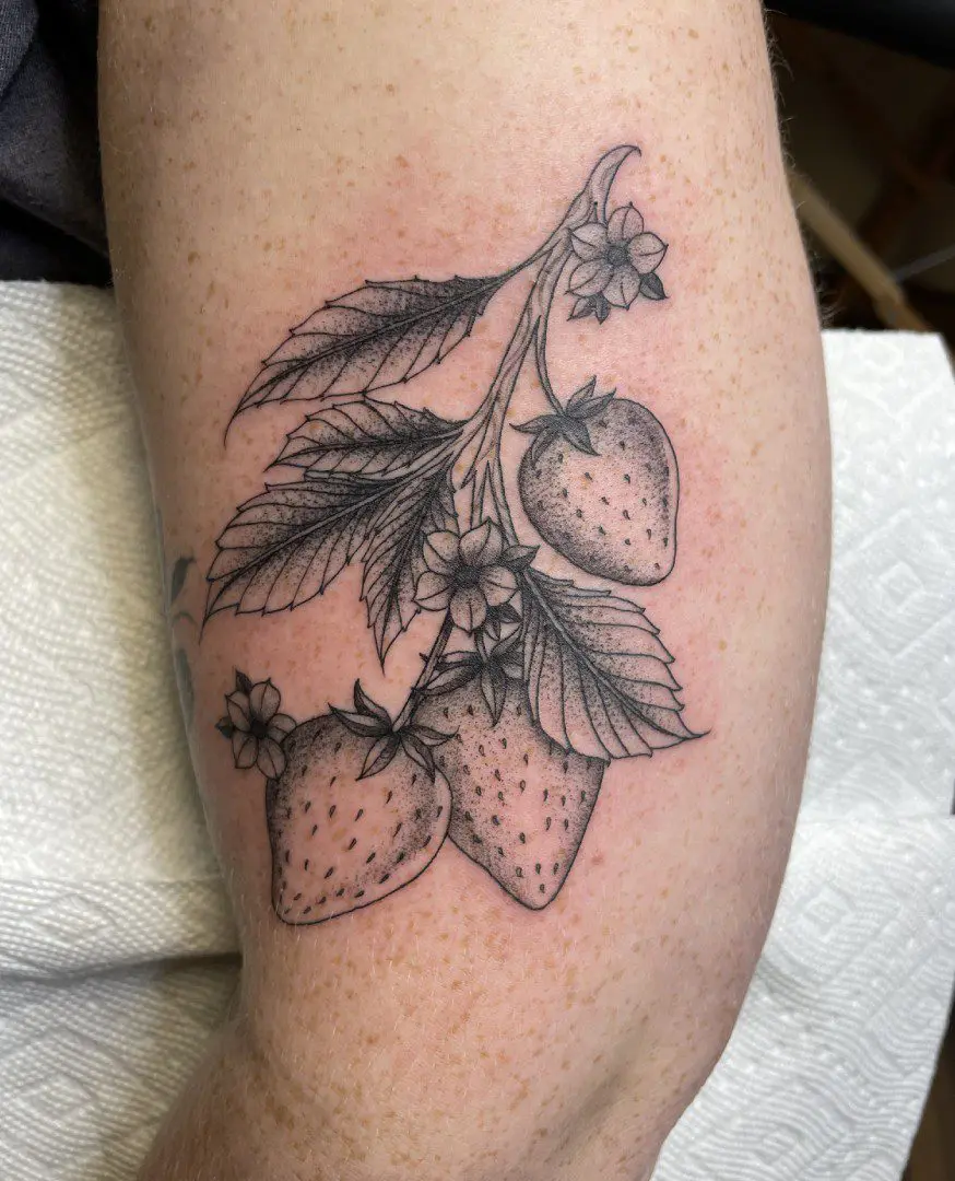 A black and white tattoo of strawberries on the arm.