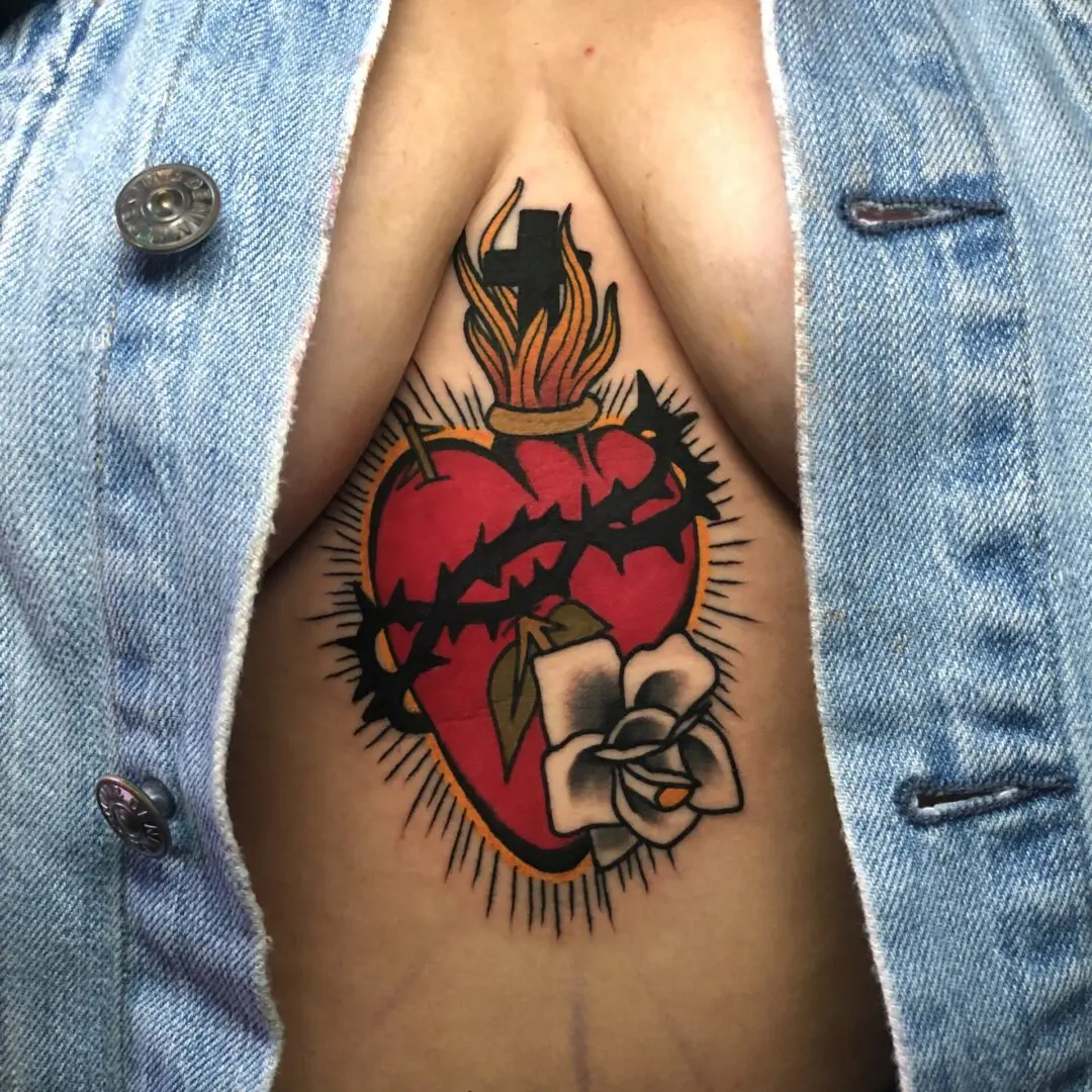 A woman with a heart tattoo on her chest. Best American Traditional Tattoo Artist- Myke Chambers