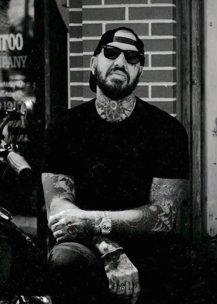 A man with tattoos sitting on the street.
