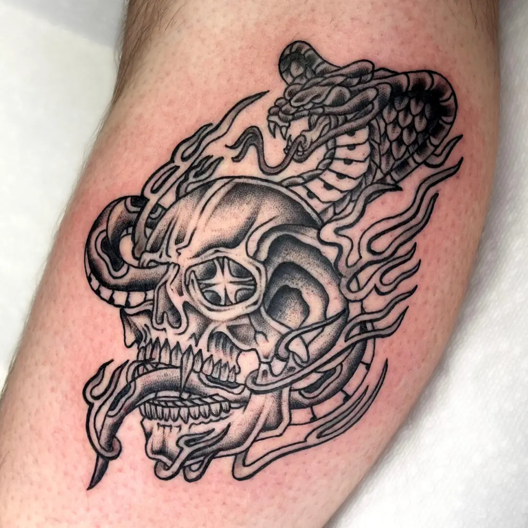 A tattoo of a skull and snake in black and gray american traditional style on the forearm.