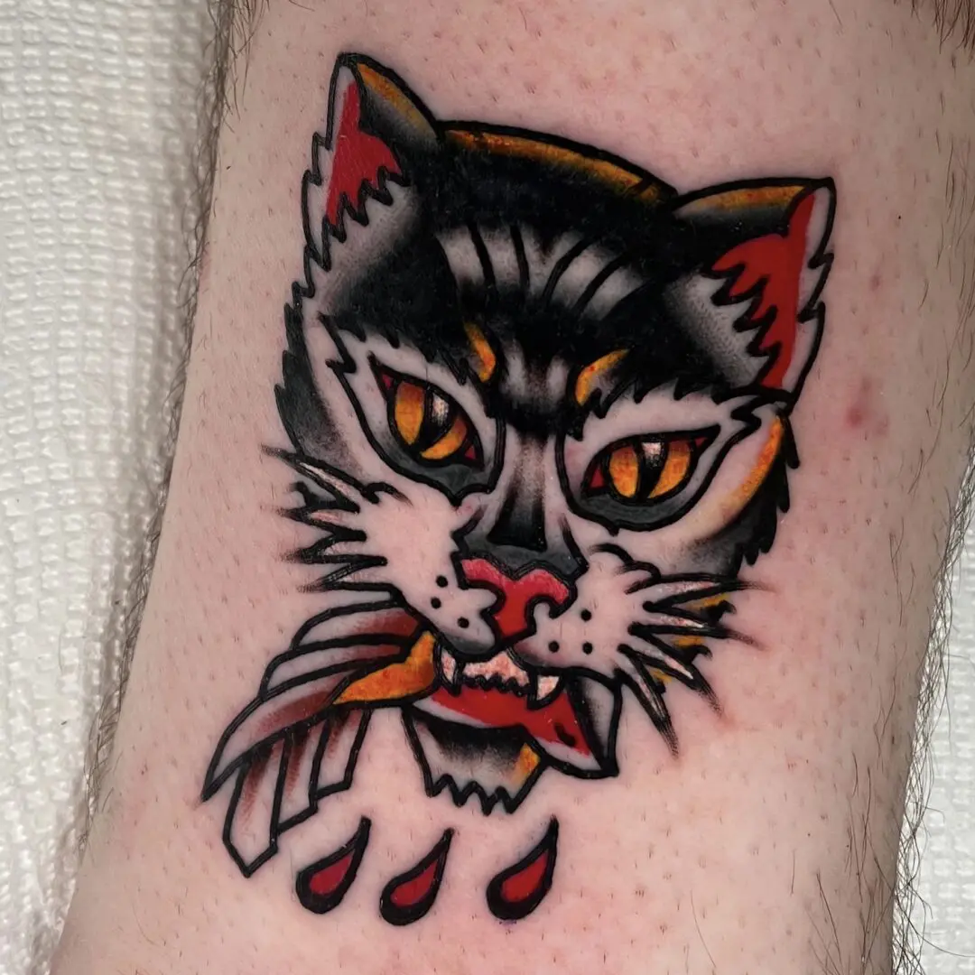 A black and gray traditional tattoo of a cat with a bloody mouth.