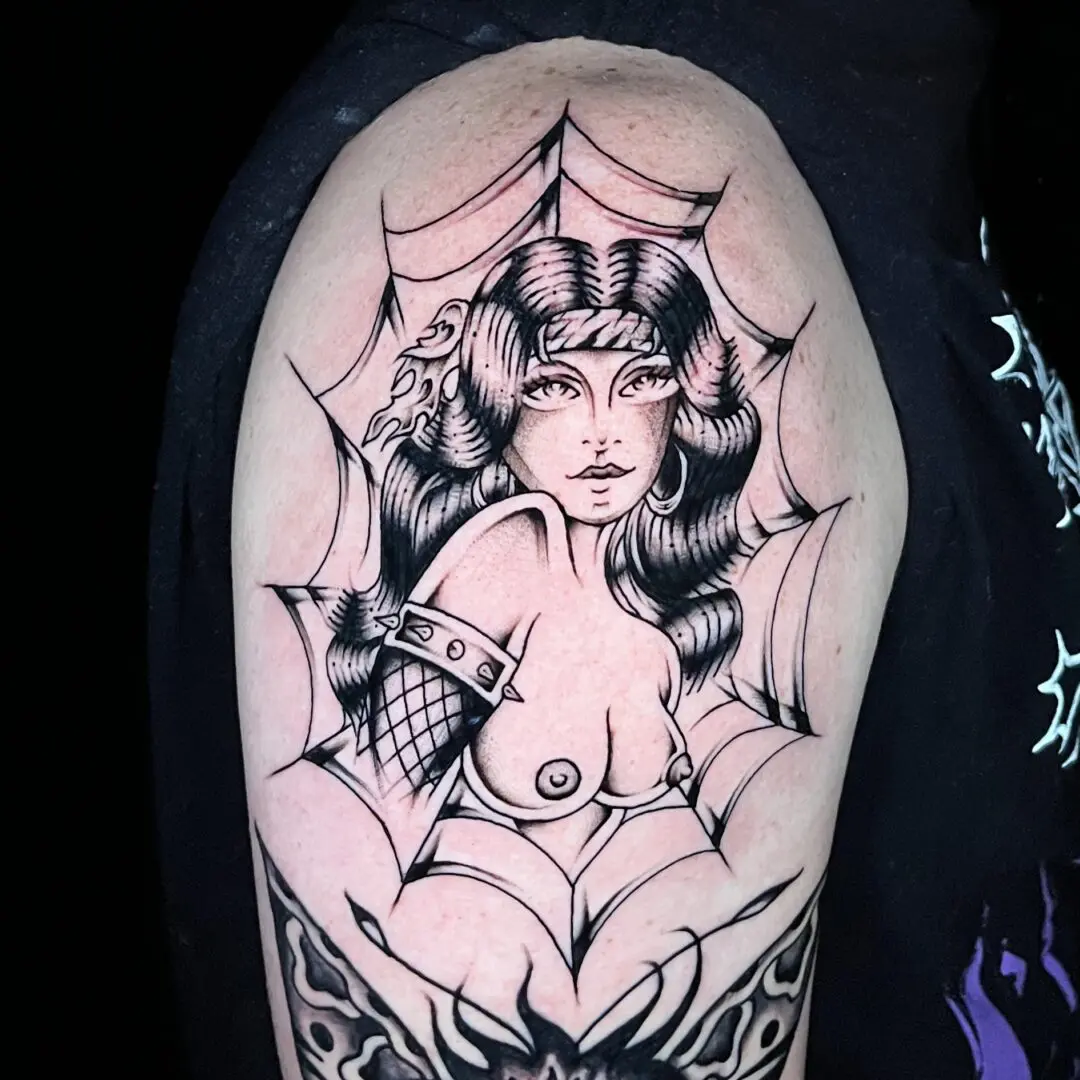 A traditional black and gray tattoo of a woman with a spider web on her arm.