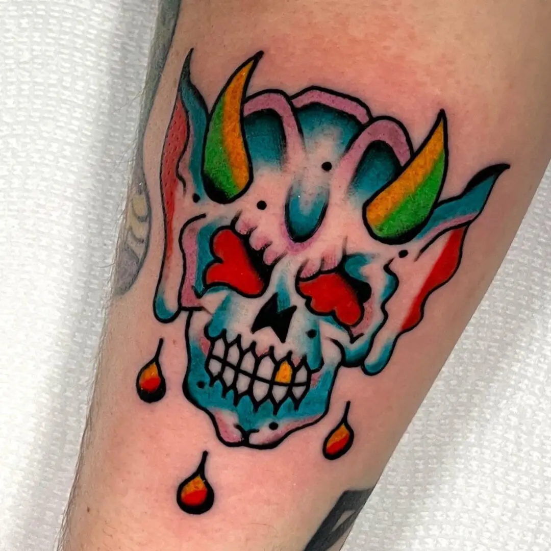A tattoo of a black and gray traditional skull with horns.
