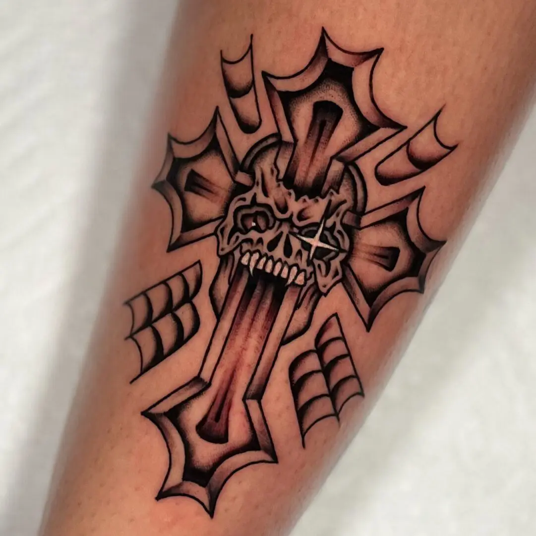 A tattoo with a skull and cross in black and gray traditional style on the leg.