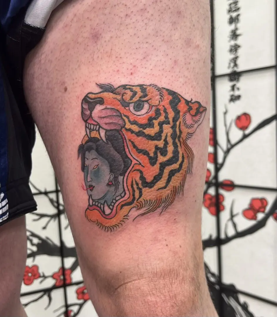Illustrative tiger tattoo on a thigh rendered in color