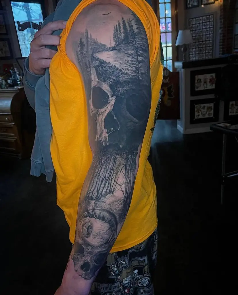 A man wearing a yellow shirt with a skull tattoo on his sleeve, showcasing the work of one of the best realism tattoo artists in Philadelphia.