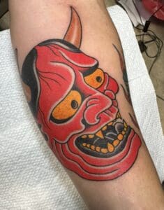 Red demon tattoo with yellow eyes.