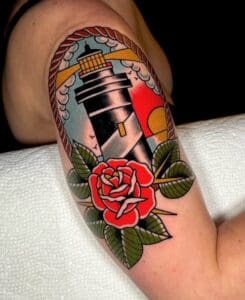 Tattoo of lighthouse and rose on arm.