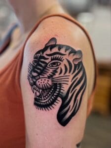Tiger tattoo on person's upper arm.