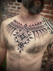 Geometric chest tattoo on bearded man.