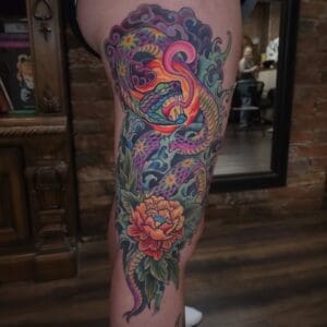 Colorful snake and flower tattoo on thigh.