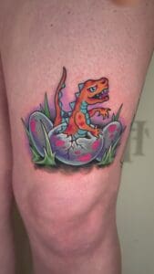 Colorful dinosaur tattoo on someone's knee.